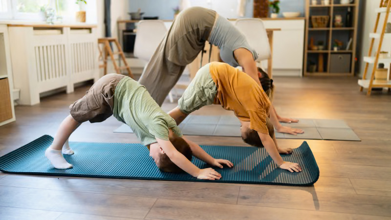 Børn laver yoga på måtter sammen med en voksen